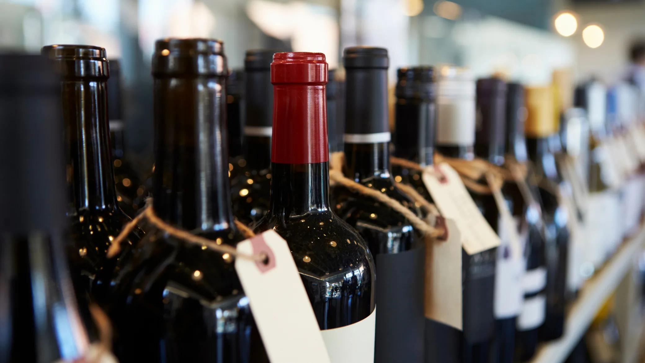 Garrafas de vinho com etiquetas em prateleira, ilustrando o case de estratégia D2C em alimentos e bebidas